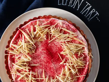 Lemon tart with white chocolate curls and raspberry dust
