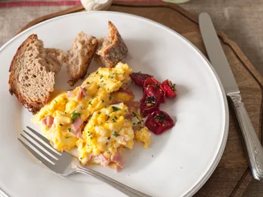 Scrambled creamy eggs with ham, cheddar and roasted tomatoes
