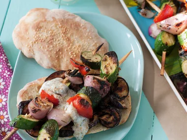 Grilled eggplant with vegetable skewers on flat bread
