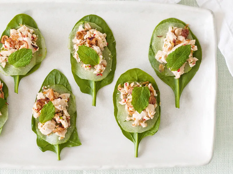 Shredded chilli and lime chicken, with crispy shallots on spinach leaves