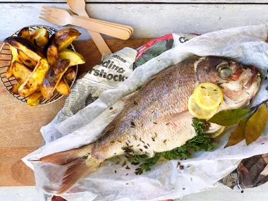 Whole paper-baked fish with potato skins and tartare