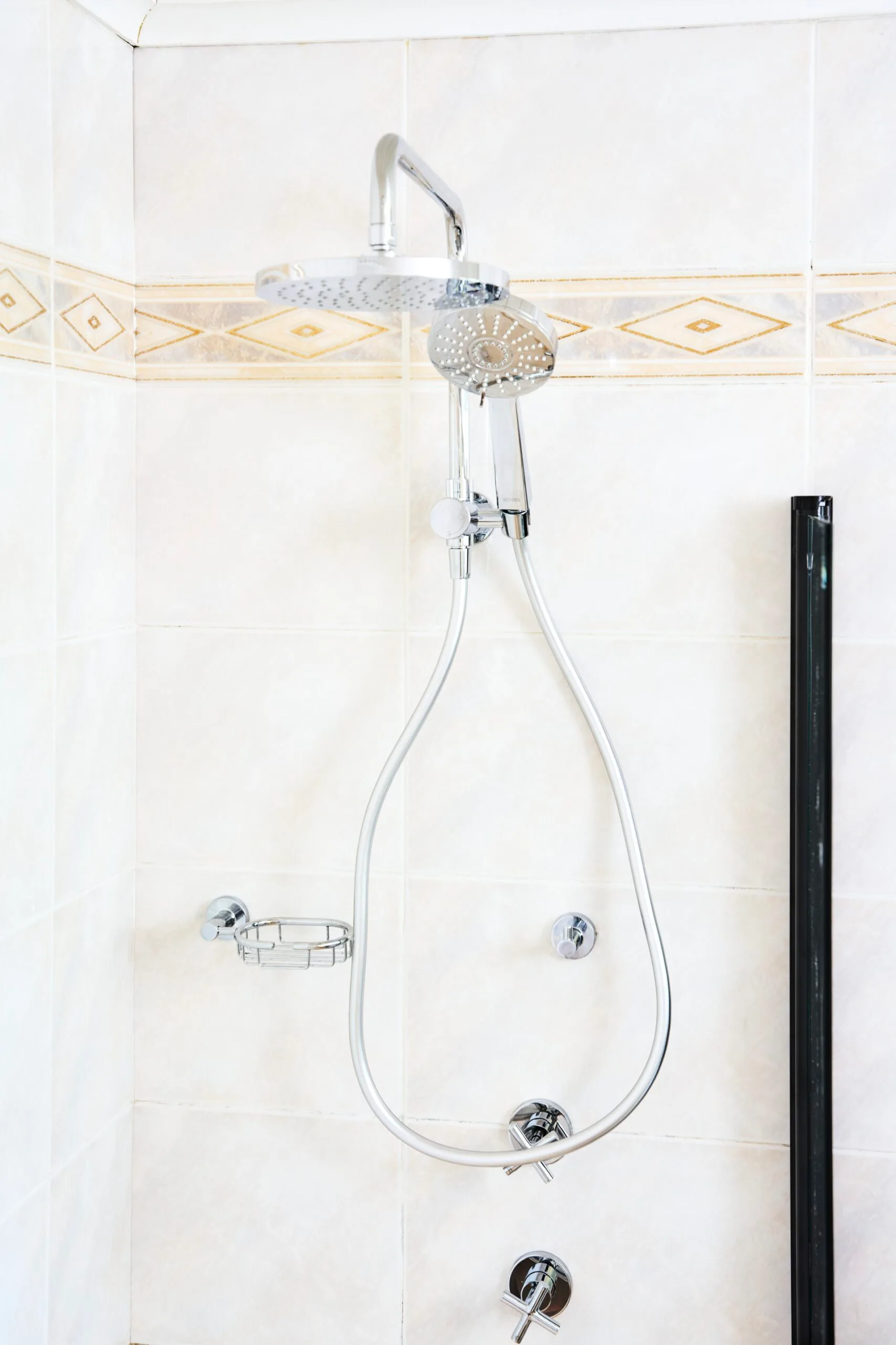 close up of shower head with white bathroom tiles