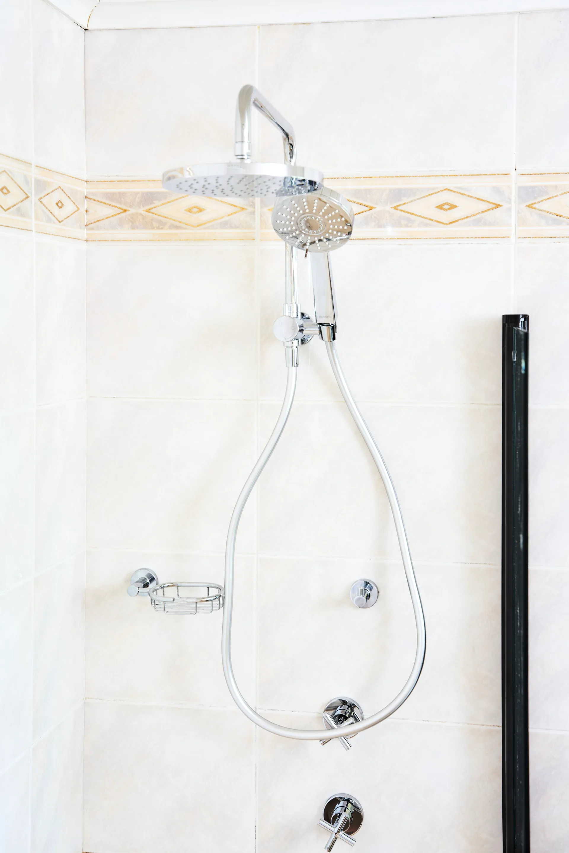 close up of shower head with white bathroom tiles