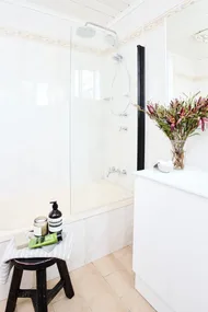 side shot of venity with black stool and bath/shower in the background