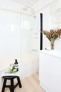 side shot of venity with black stool and bath/shower in the background