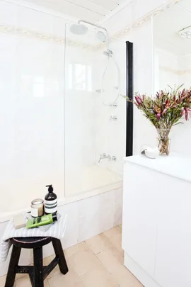 side shot of venity with black stool and bath/shower in the background