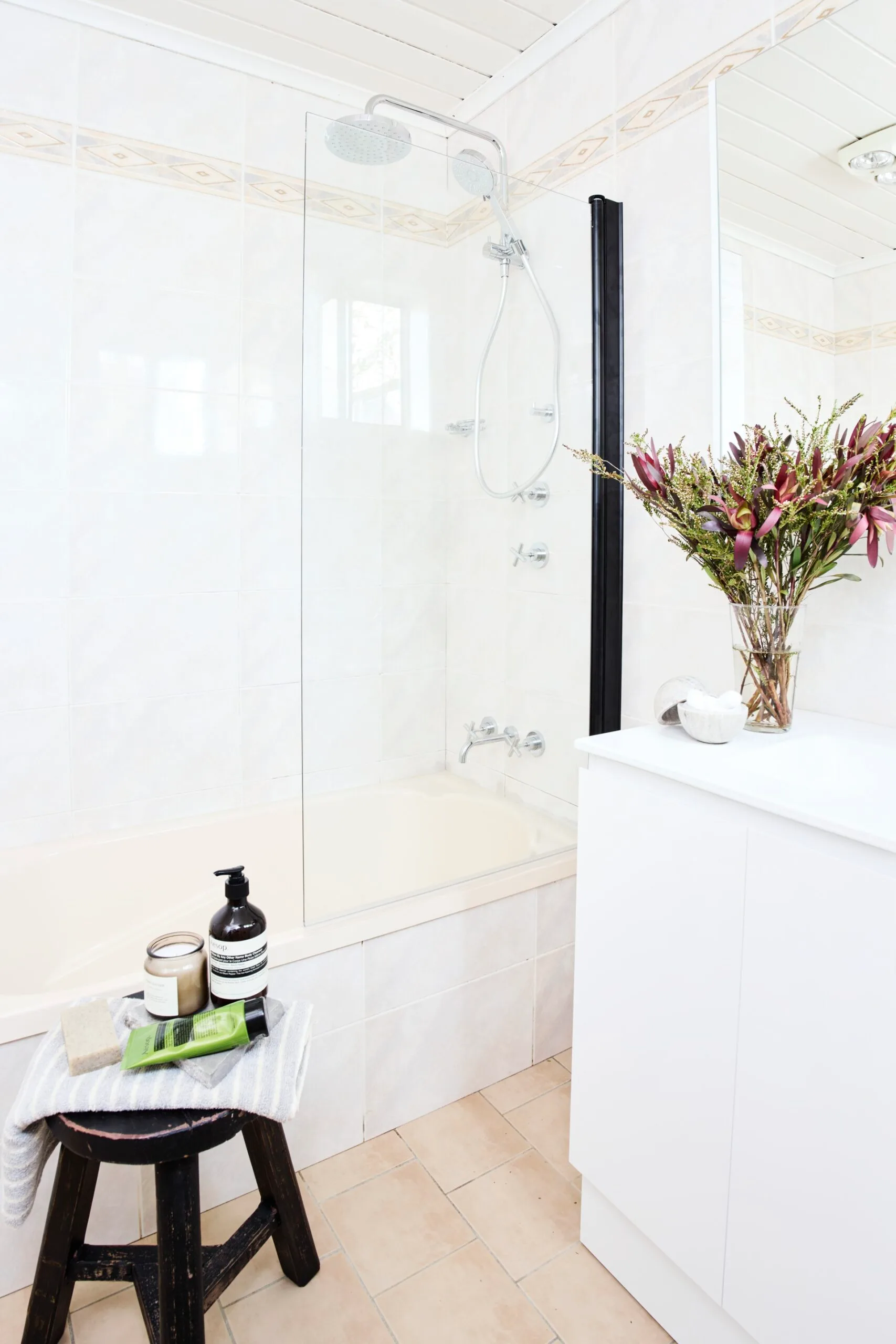 side shot of venity with black stool and bath/shower in the background