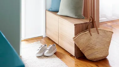 Home entranceway with a pair of shoes on the floor and a bag next to a bench.