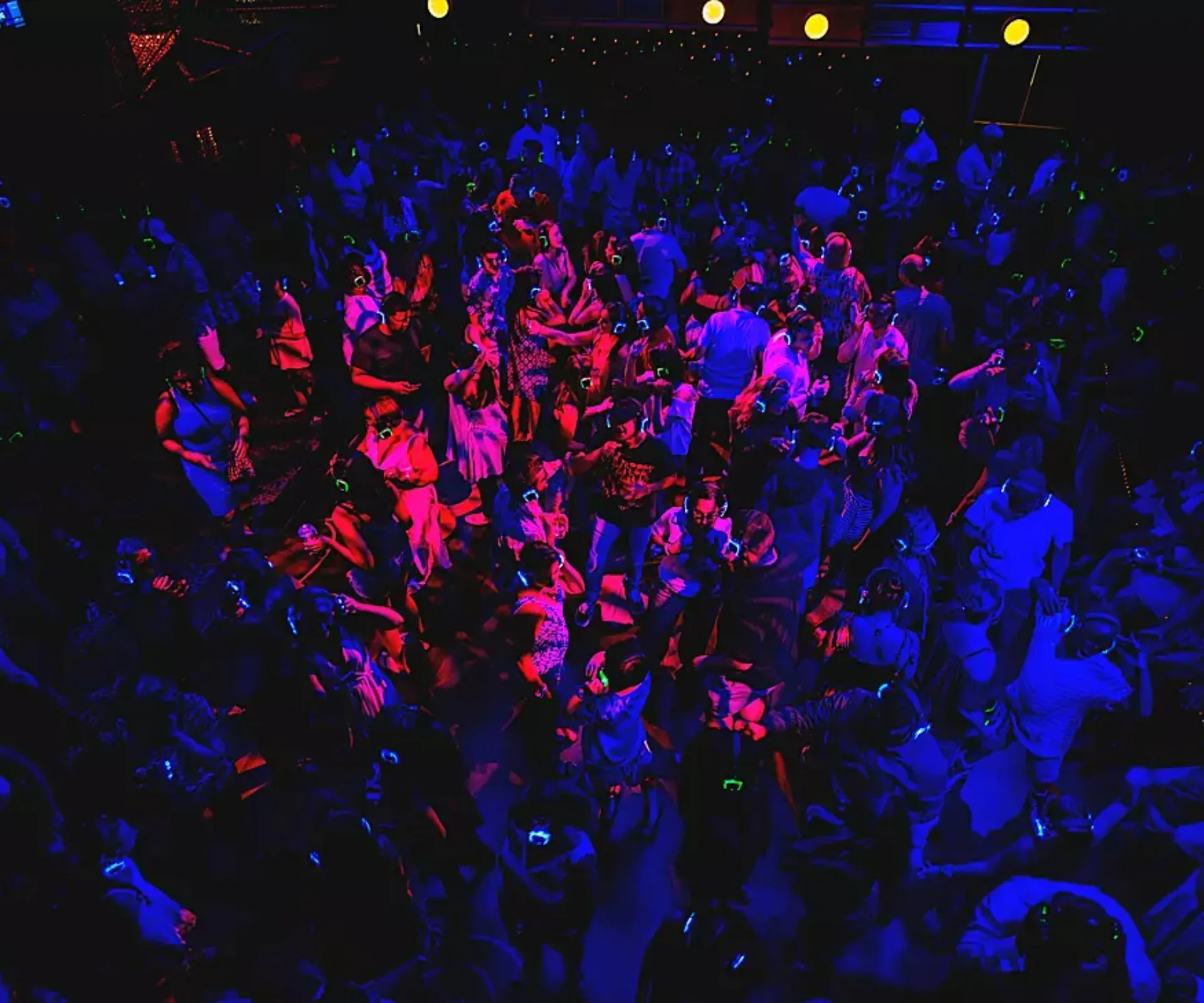Crowd of people partying at a silent disco on board a cruise ship with red and blue strobe lights
