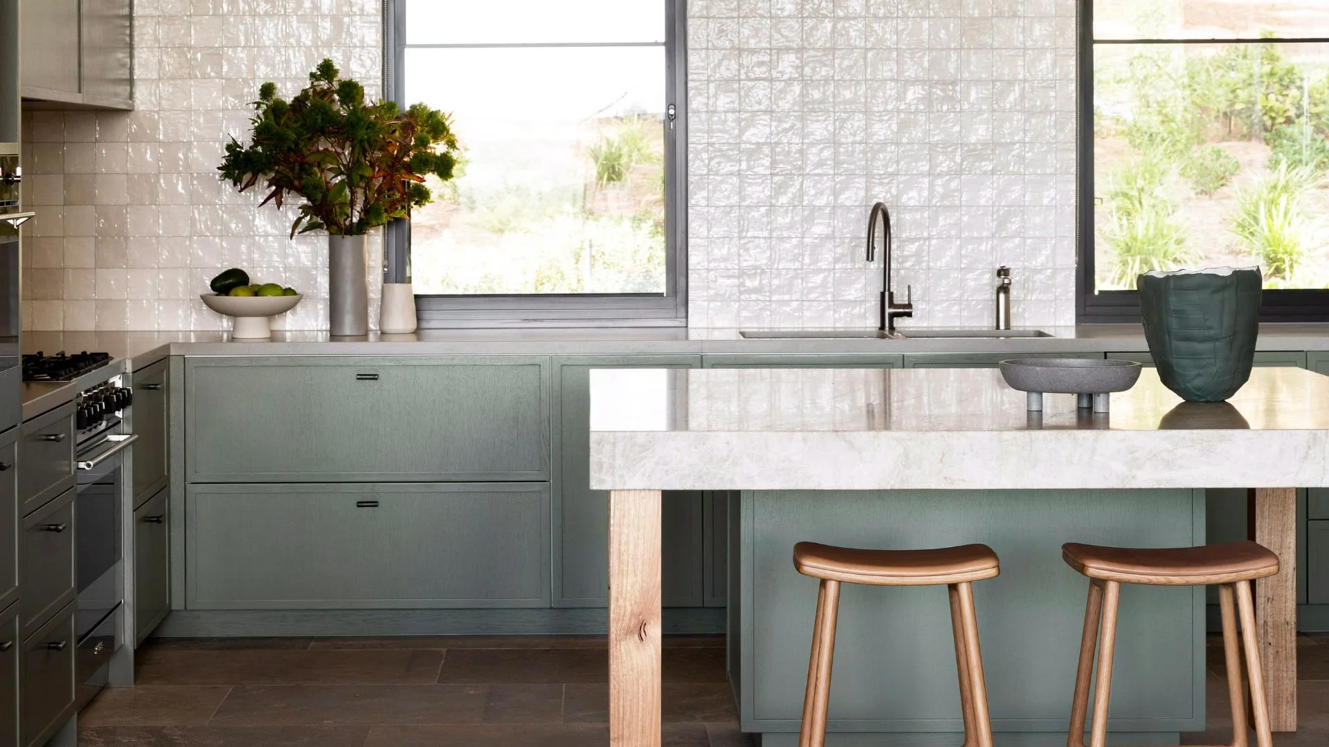 green kitchen with marble island and bar stools