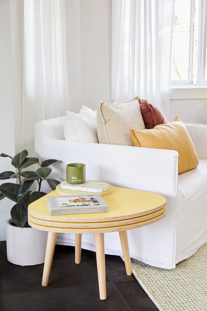 yellow side table styled living room decor with white armchair and mustard coloured pillows