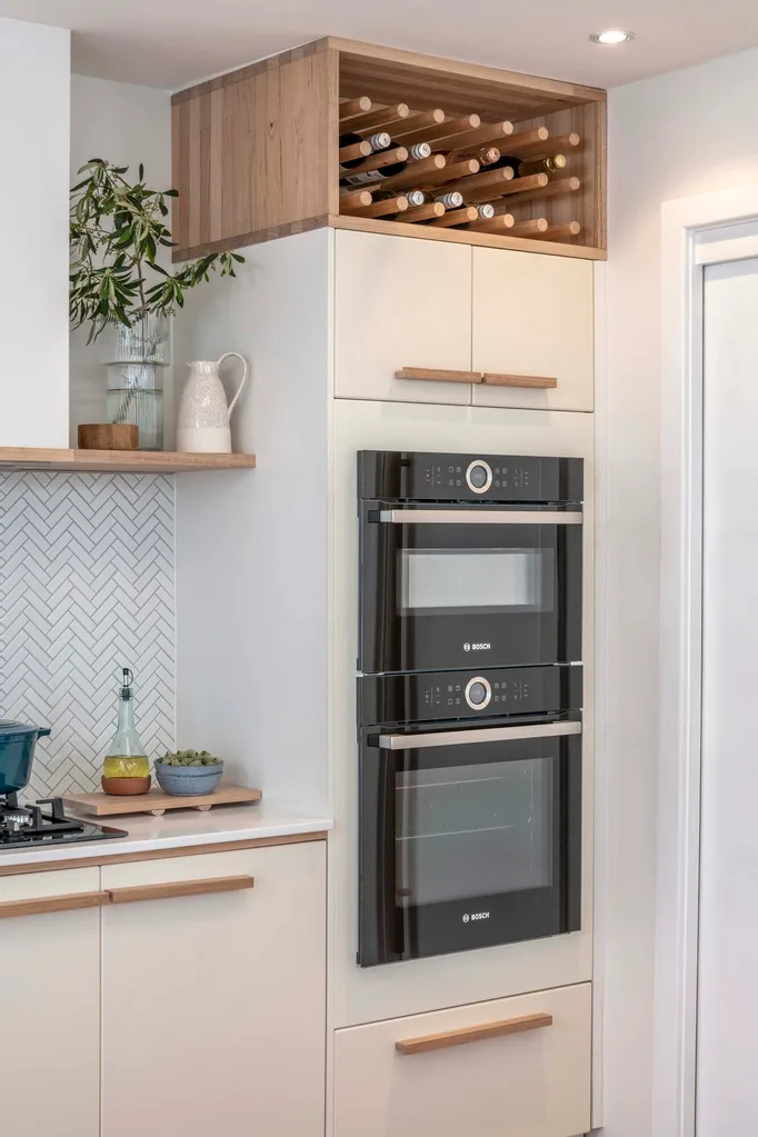 Small kitchen with stacked oven and convection oven to save space. Above the oven is a small cabinet and an open-shelf for storing wines.