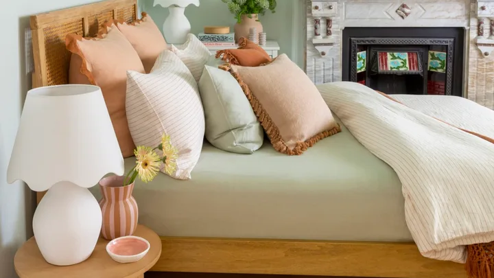 blue painted bedroom with sage green bed in the middle and neutral coloured cushions