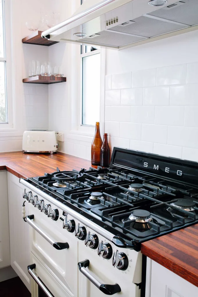 Modern farmhouse style kitchen with timber benchtops and a stainless steel range hood over a freestanding Smeg gas cooker