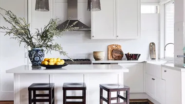 Modern white kitchen with stainless steel range hood filter that needs to be cleaned