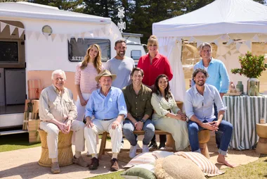 cast of better homes and gardens sitting in front of two caravans in sunlight