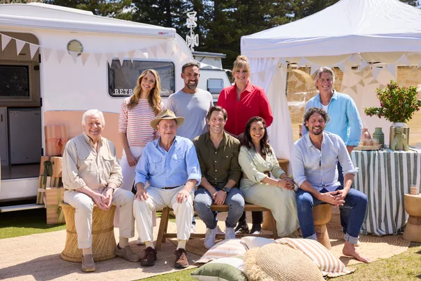 cast of better homes and gardens sitting in front of two caravans in sunlight