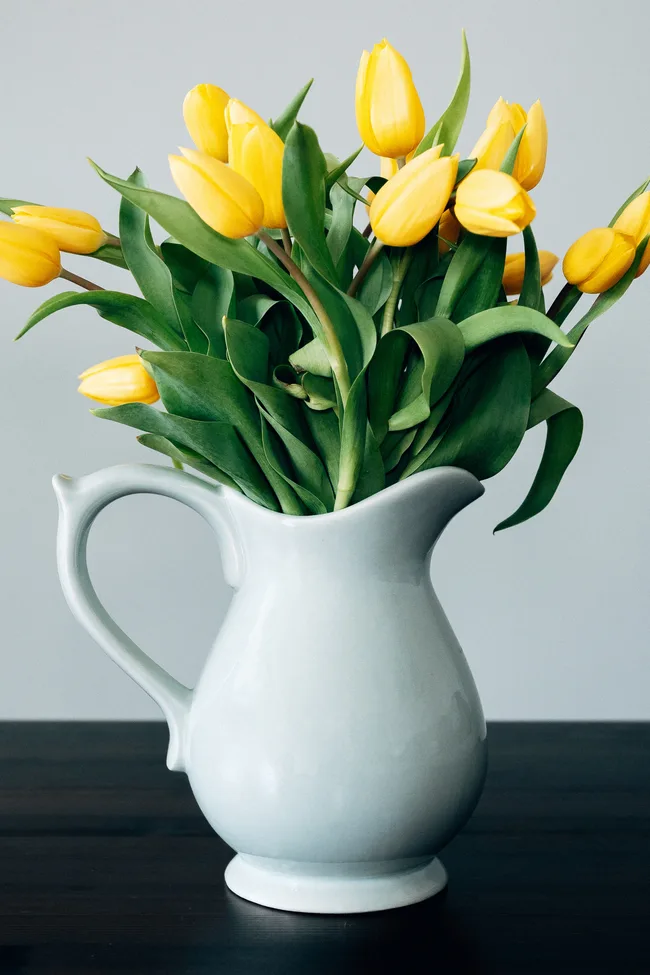 A white glass vase with yellow tulips