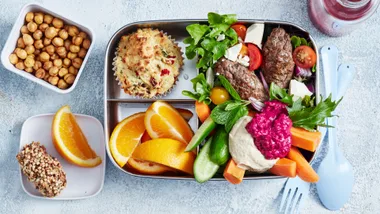 bento box meal prepped with hummus, vegetables, fruit and snacks