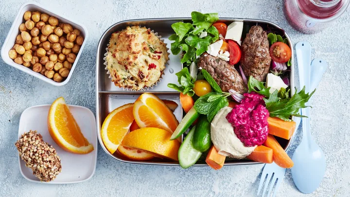 bento box meal prepped with hummus, vegetables, fruit and snacks