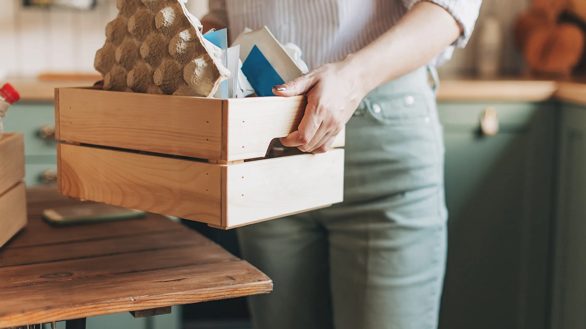 Woman holding crate filled with items to recycle