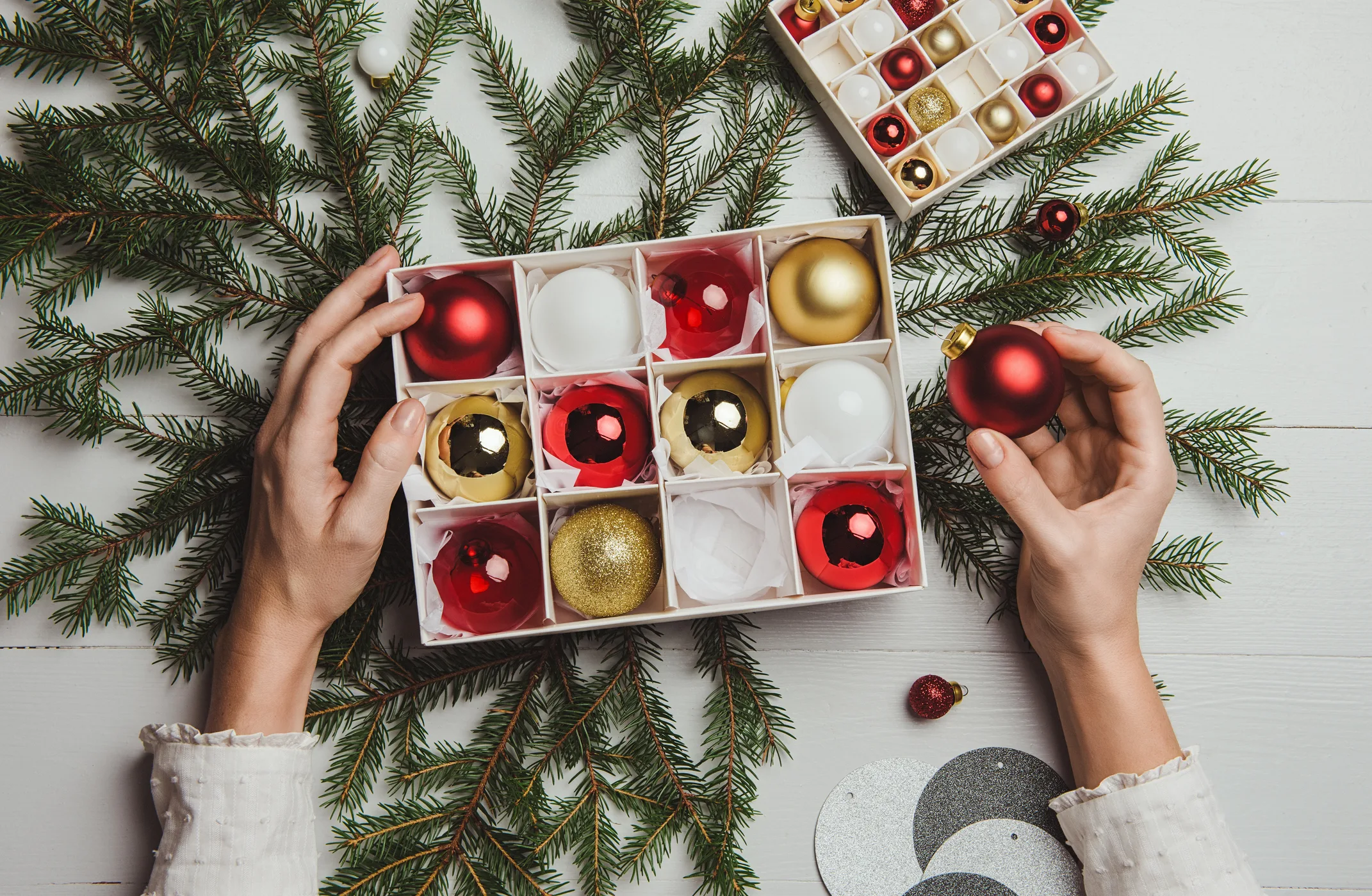 Hands placing Christmas baubles into a cardboard storage box