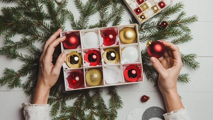 Hands placing Christmas baubles into a cardboard storage box