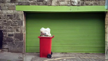 red wheelie bin in front of a green garage door