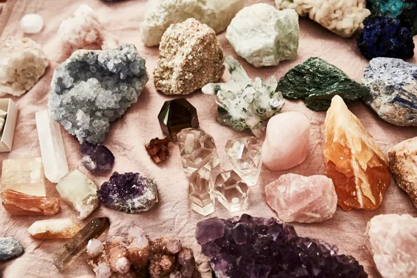 assortment of crystals and rose quartz against a pink textile background