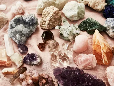 assortment of crystals and rose quartz against a pink textile background