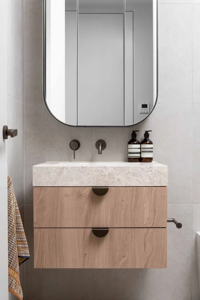 Floating timber vanity with black handles and aged brass tapware