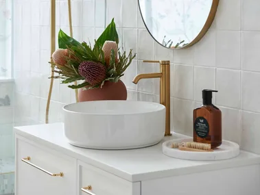 Renovated warm white modern bathroom with white vanity and basin and gold tapware