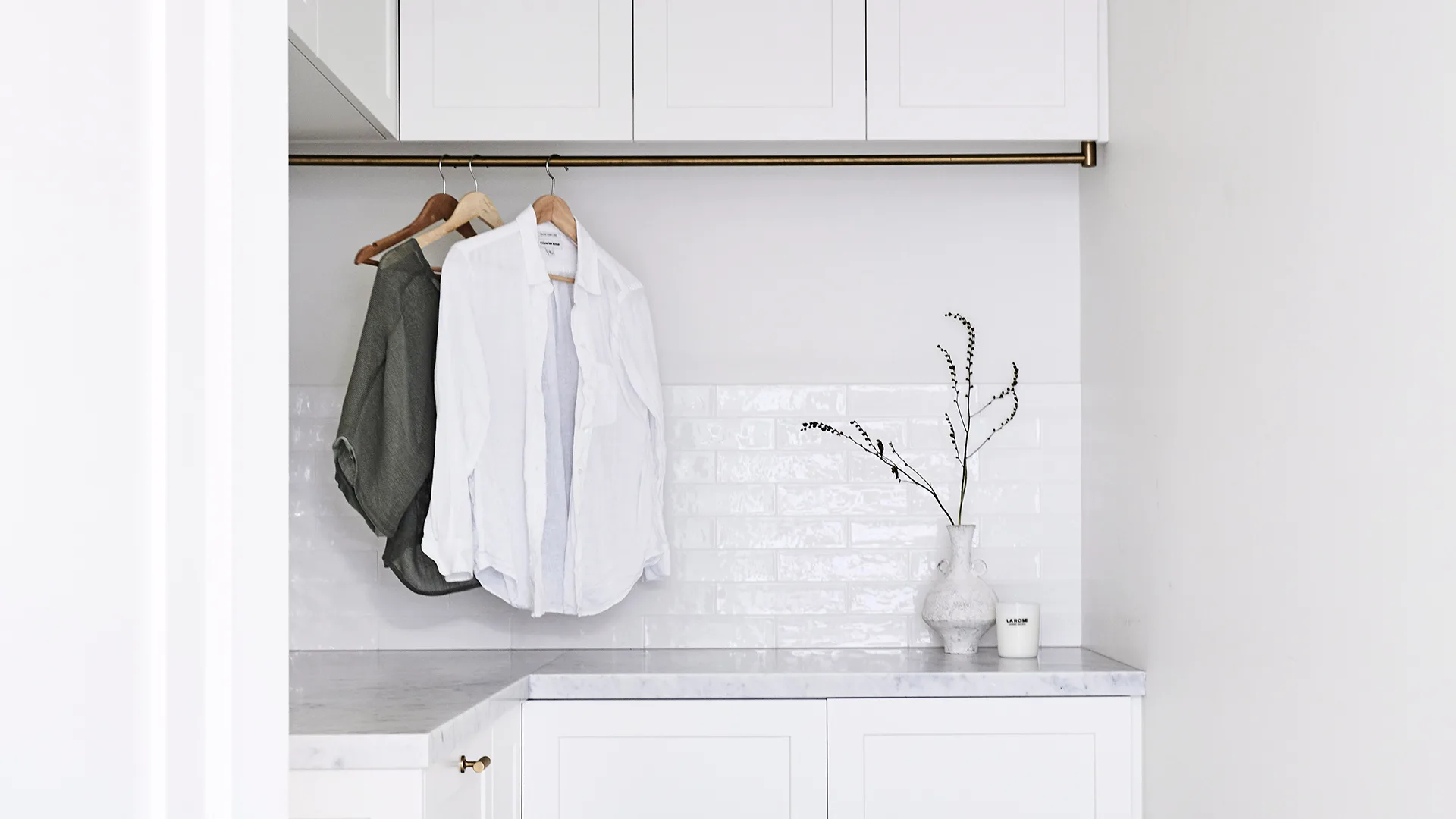 White, modern laundry with clothes hanging from an indoor rail