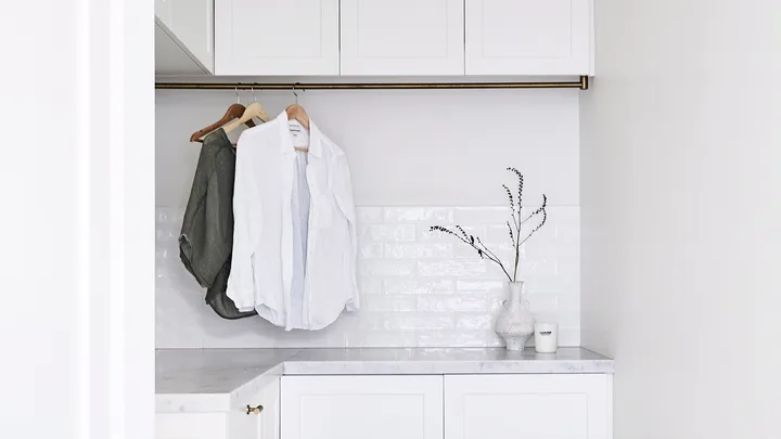 White, modern laundry with clothes hanging from an indoor rail