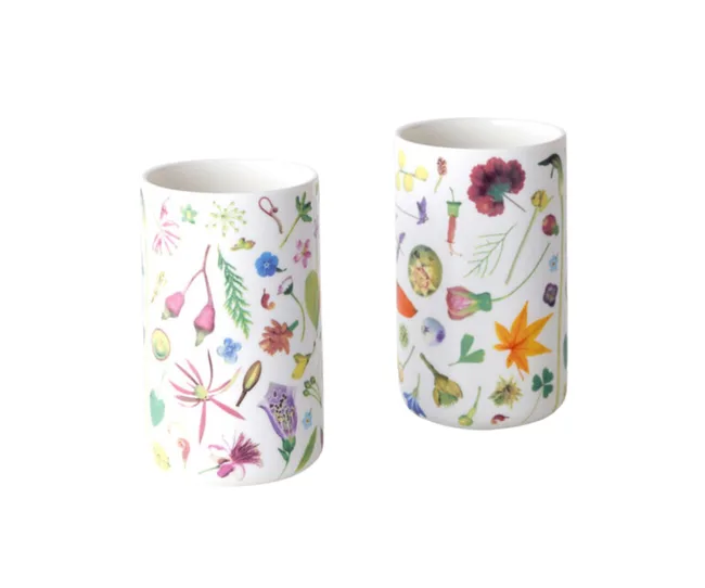 Two white ceramic cups adorned with colorful floral and botanical print designs.