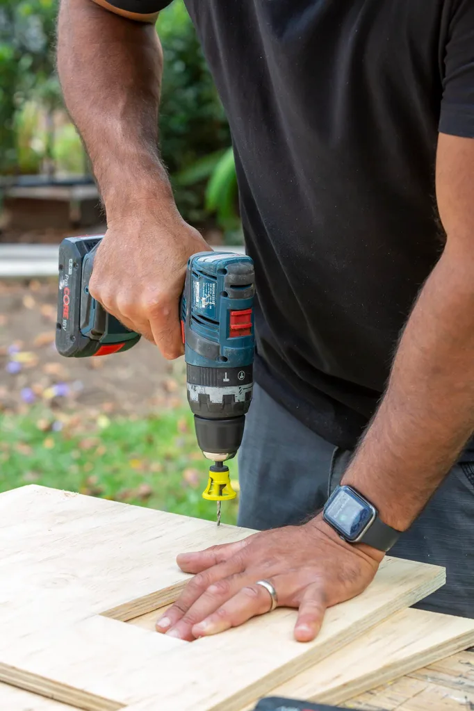 Adam Dovile drilling wood panels to create a dog kennel