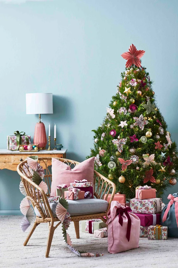Christmas tree with paper poinsettias against a blue wall