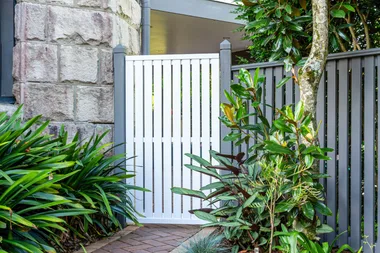 wooden gate with metal frame surrounded by green plants