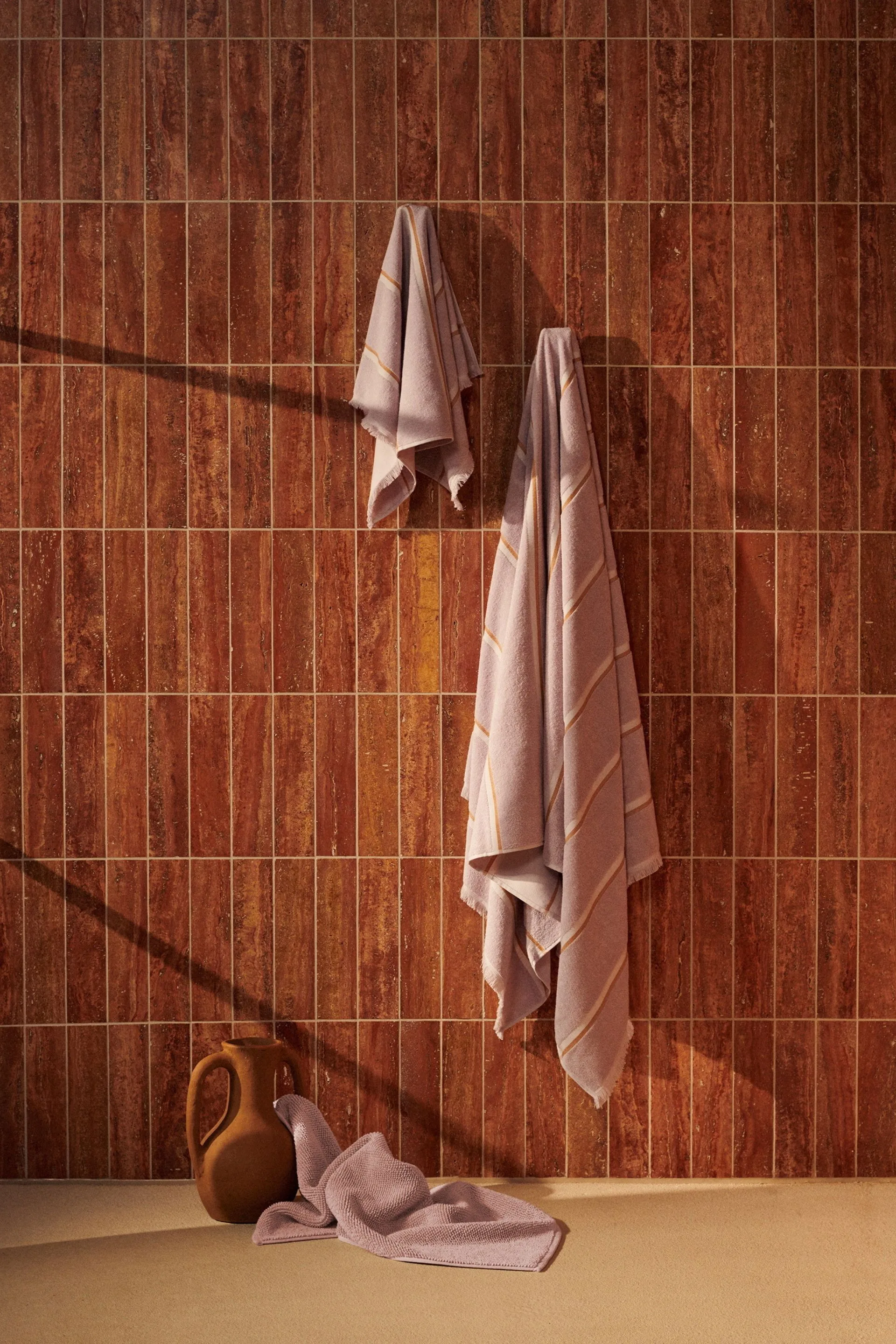 towel hanging on a hook with burnt orange tiled wall