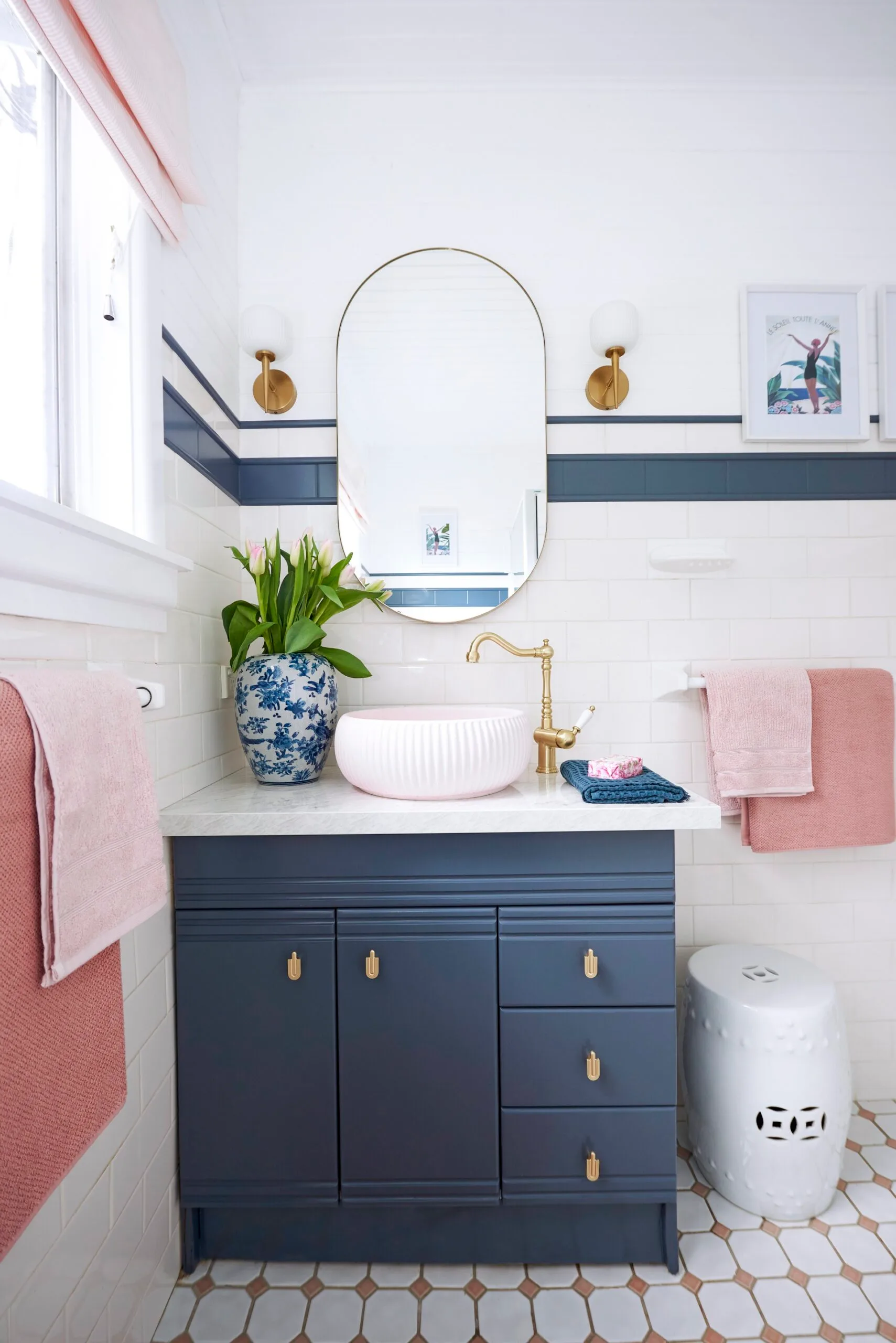 blue gold and light pink small bathroom with oval mirror and freestanding shell pink sink 