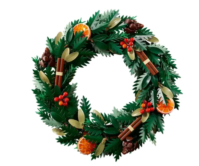 LEGO wreath with green leaves, orange slices, cinnamon sticks, and red berries, resembling festive holiday decor.