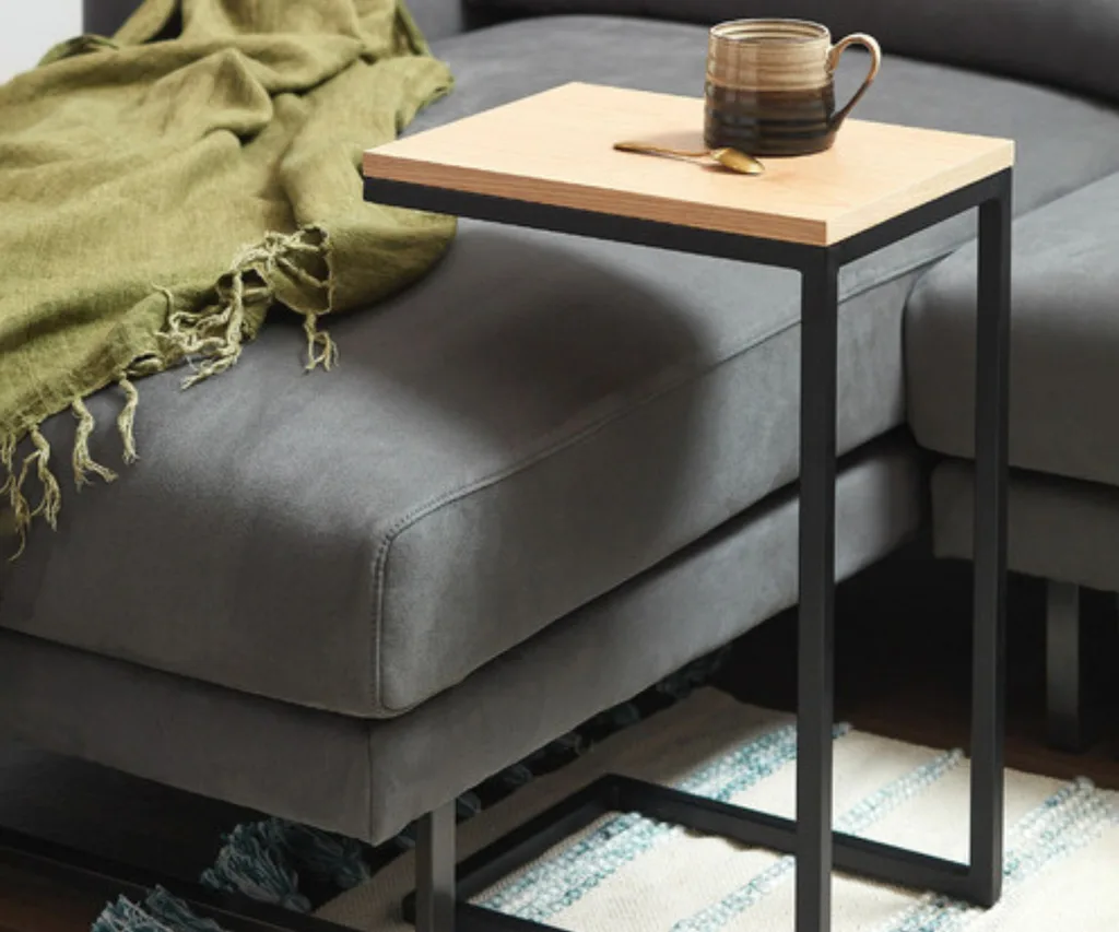 side table with metal legs going under a grey lounge with green blanket on it