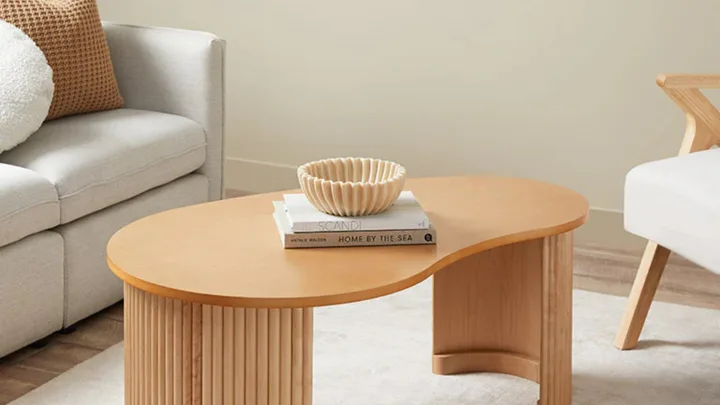 Curved, pebble-shaped timber coffee table in a neutral living room.