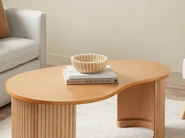 Curved, pebble-shaped timber coffee table in a neutral living room.