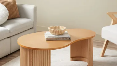 Curved, pebble-shaped timber coffee table in a neutral living room.