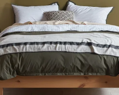 olive and white sheets on a natural wooden bed frame