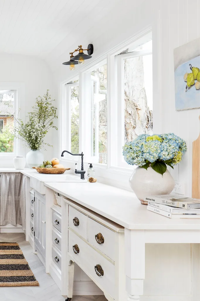 new kitchen with wooden white painted cabinets with hydrangeas in a pot