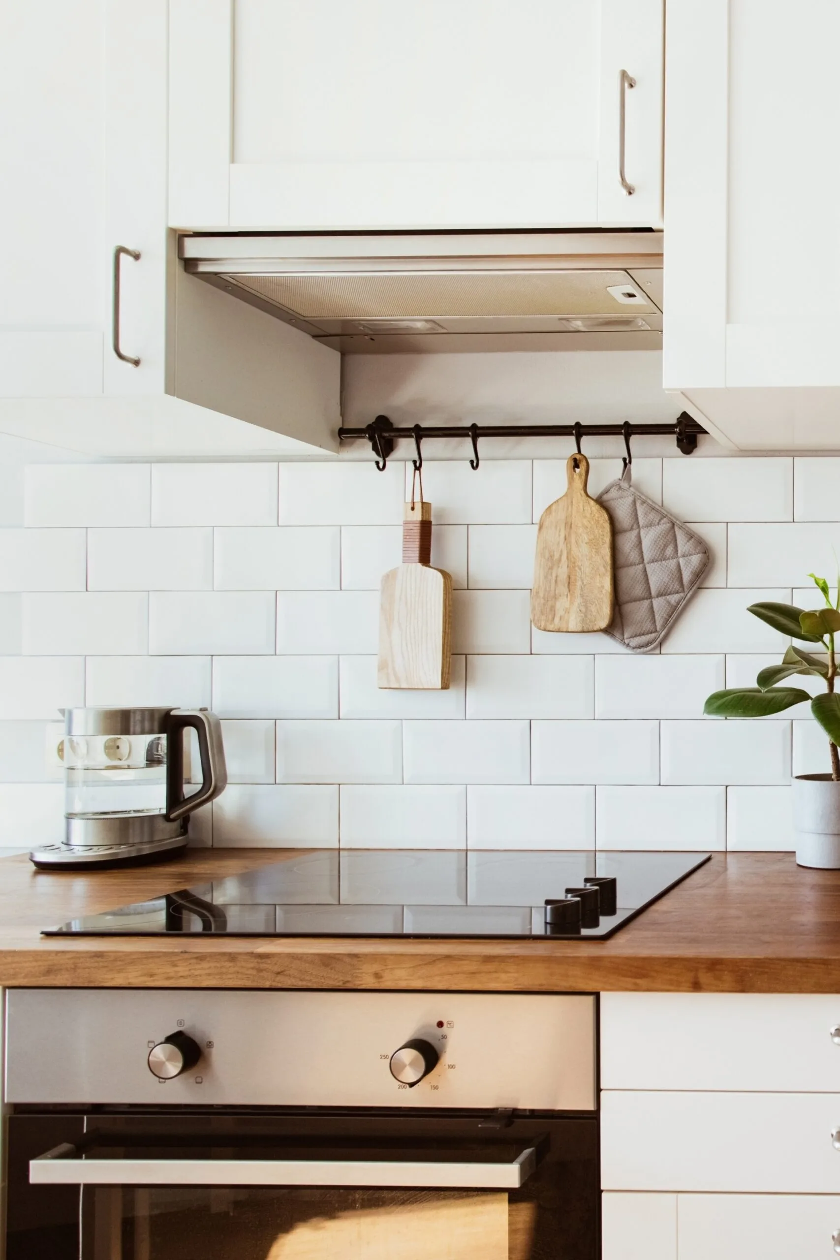 white kitchen with subway tiles backsplash and clear glass electric kettle to the left 