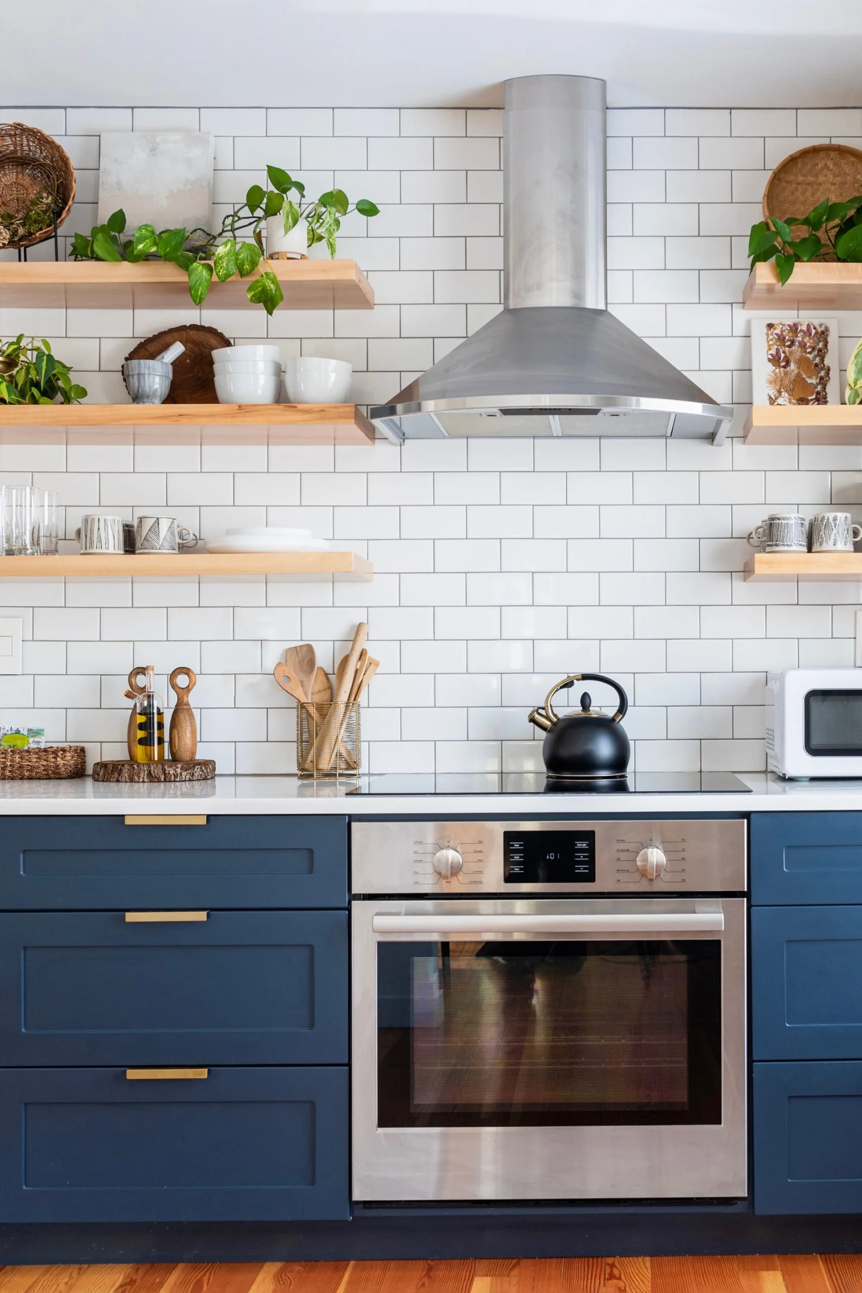 subway tile kitchen with dark blue cabinetry, with black stovetop kettle on the induction stove