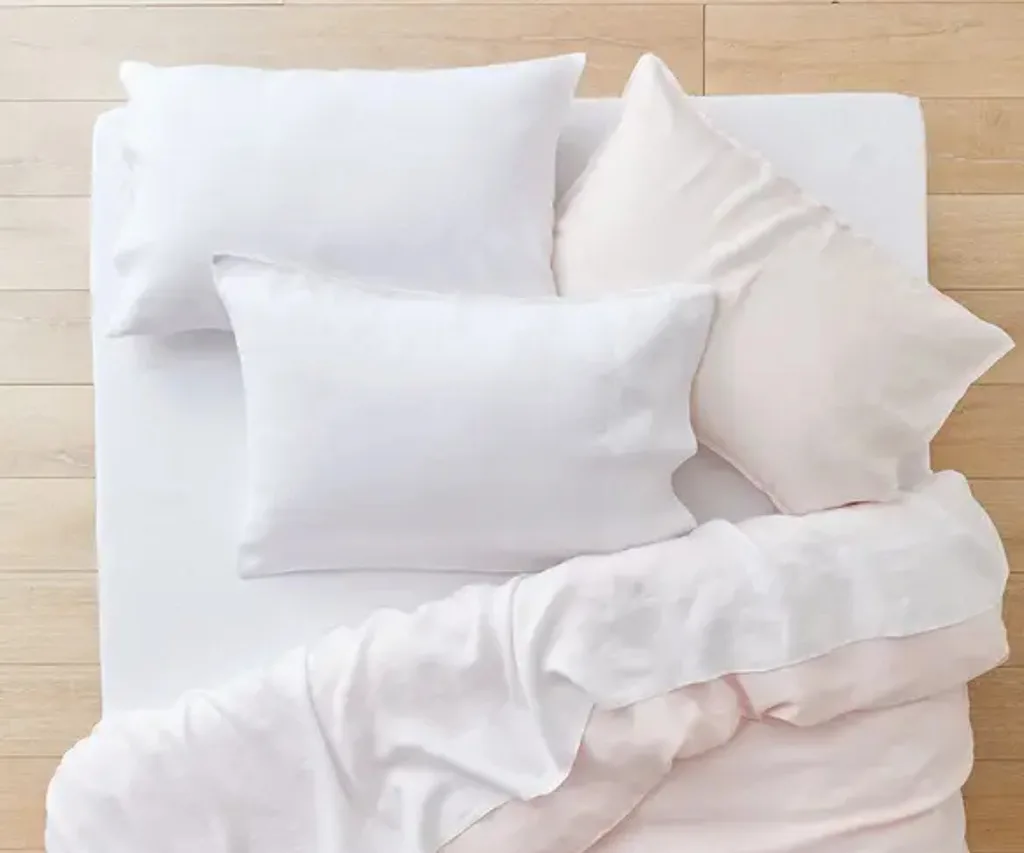 overhead shot of three white pillows and folded over quilt set